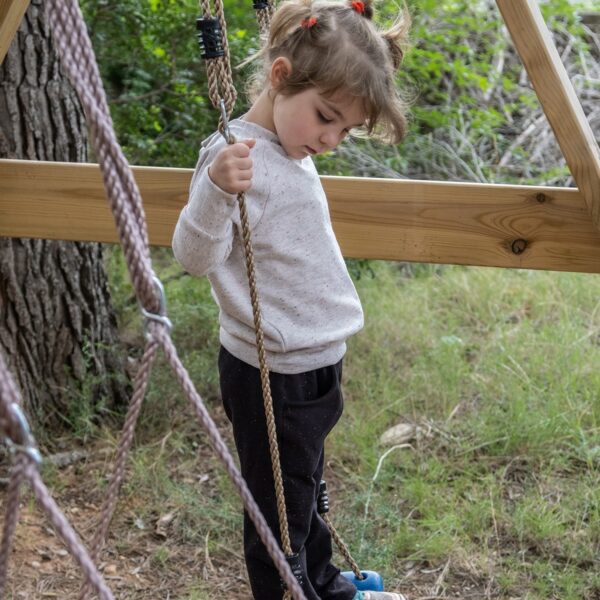 Girl on a swing wearing a white sweatshirt and black pants from the Jalabí collection by ToTó