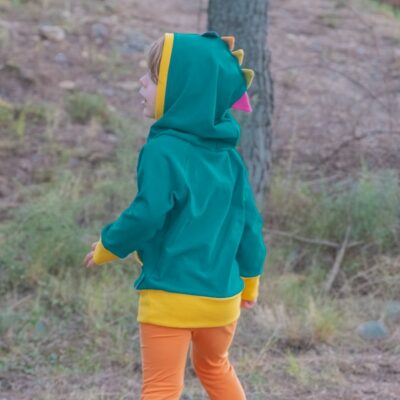 Girl dressed in ToTó's hooded sweatshirt with dinosaur crests in petrol.